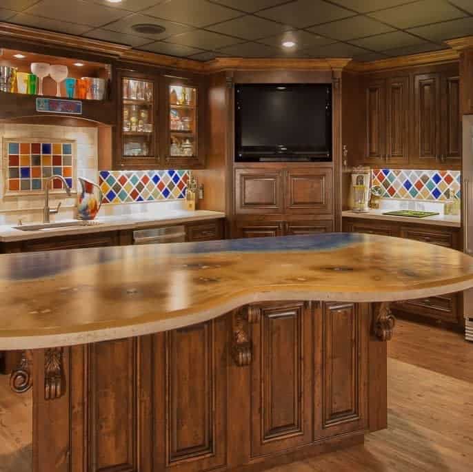 A traditional wood wet bar with colorful tile backsplash, a curved countertop, and built-in cabinetry.