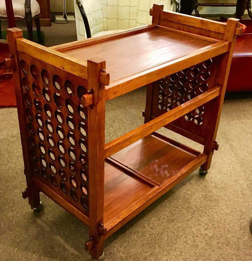 Traditional wooden bar cart with lattice sides and two shelves for storage.