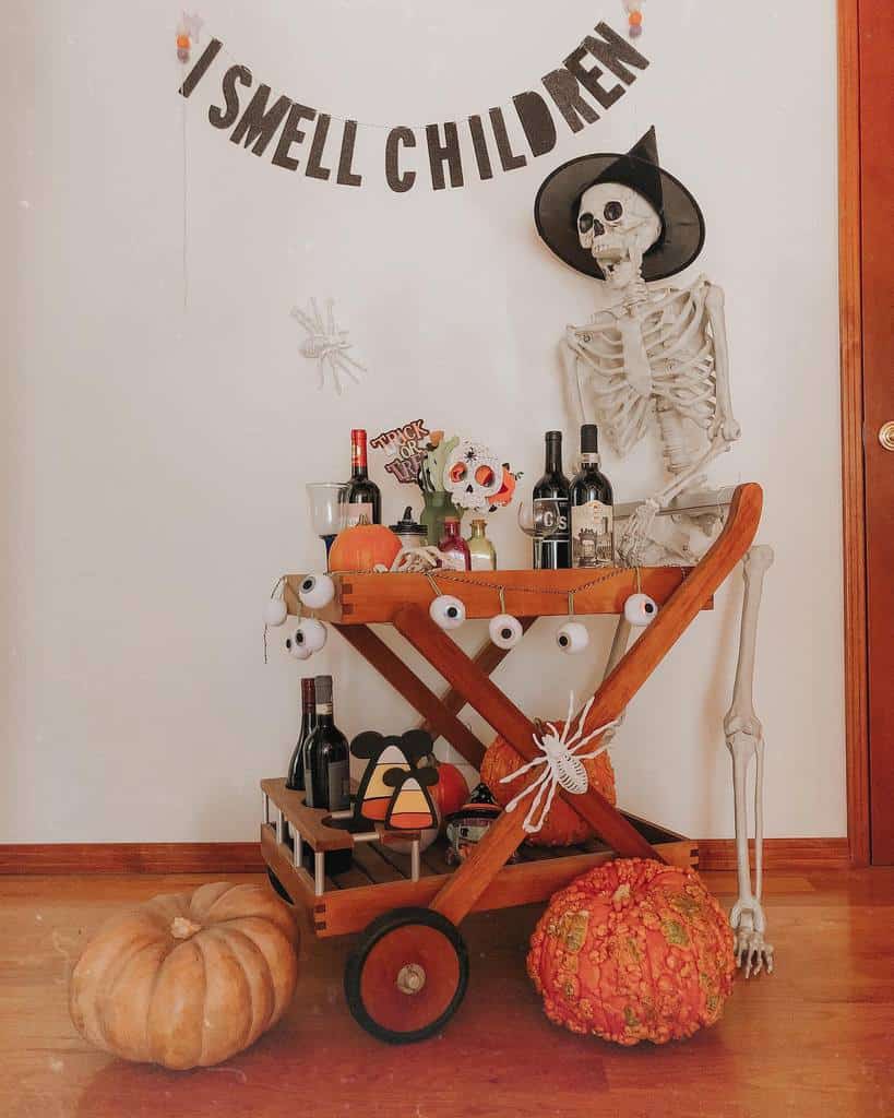 Halloween-themed wooden bar cart decorated with skeleton, pumpkins, and spooky eye ornaments.