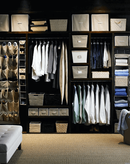 Organized walk-in closet with neatly hung shirts, baskets, and folded clothes in neutral tones